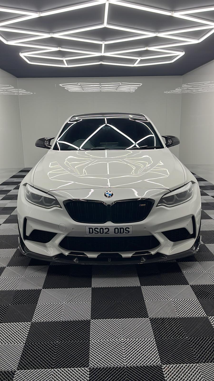 White BMW M2 with a Gtechniq ceramic coating showing mirror-clean reflection inside a detailing studio